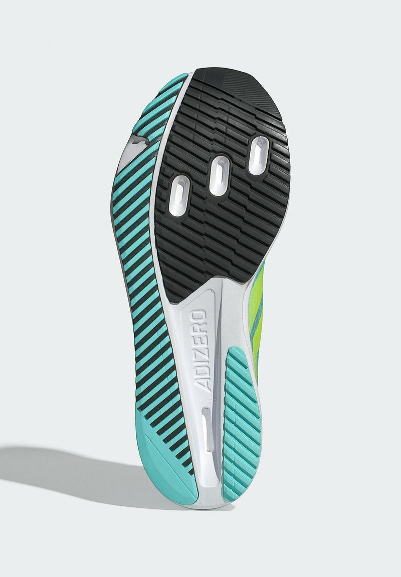 Suela de zapatilla de correr ligera que presenta una banda de rodadura de goma negra con acentos en turquesa y blanco, surcos horizontales y verticales, y agujeros de ventilación.