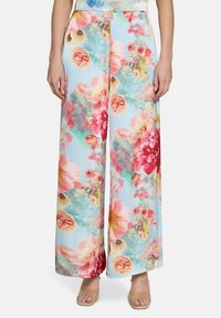 Pantalon ample léger et fluide de couleur bleu pastel avec de grands motifs floraux dans des teintes roses, orange et jaunes. Tissu lisse, ceinture élastique.
