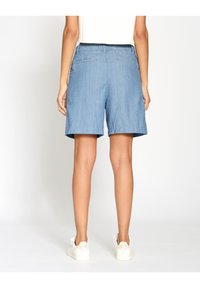 Džínové šortky v světlé modré barvě, s uvolněným střihem, středně vysokým pasem a dvěma zadními kapsami. Hladká textura a jednoduchý design bez vzorů.