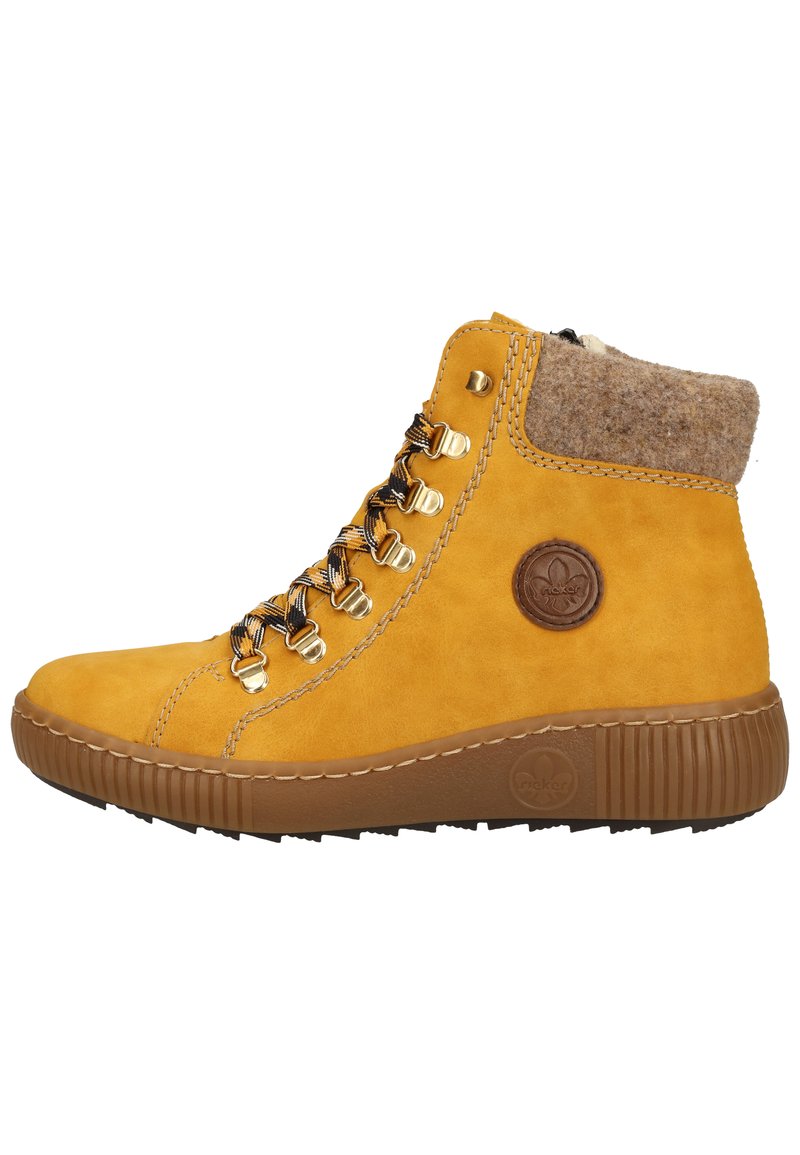 Bottes à la cheville en daim jaune avec un col en laine, semelle en caoutchouc marron, accessoires dorés et lacets noir et blanc. Logo en relief sur le côté.