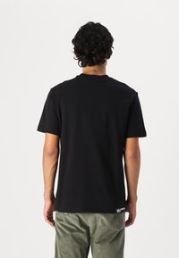 Zwarte katoenen t-shirt met korte mouwen en ronde hals, met een rechte snit en zichtbare stiksels aan de zoom.