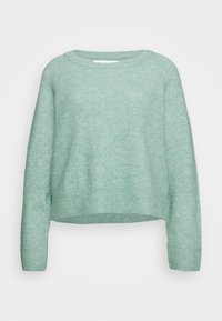 Pull en maille vert clair à manches longues avec poignets, ourlet et encolure ronde côtelés sur un fond clair uni.