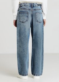 Jeans en denim bleu clair avec une coupe ample, dotés de deux poches arrière, de détails cousus et d'un ourlet effiloché aux poignets.
