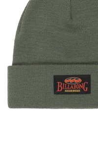 Cappello di lana verde a maglia con risvolto, caratterizzato da un'etichetta nera rettangolare con la scritta "BILLABONG" in rosso e giallo, che indica l'anno 1973.