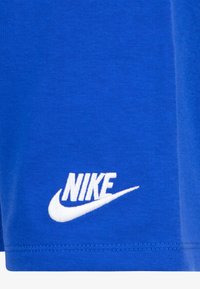 Mėlynas medvilninis marškinėliai su apvaliu iškirpimu ir trumpomis rankovėmis, turintys baltą Nike logotipą apatineje dešinėje kampo dalyje.