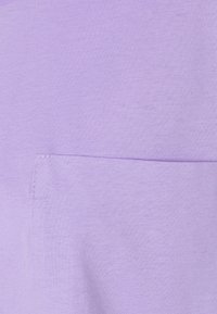 Tessuto di cotone viola chiaro con una superficie liscia, dotato di una piccola tasca applicata sulla parte anteriore. Design semplice senza motivi aggiuntivi.