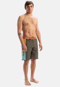 Herrbadshorts i olivgrön med orange och aqua blå accenter. Tillverkade av snabbtorkande tyg, med dragsko i midjan och sidologga.