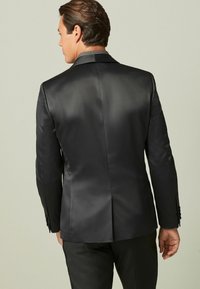 Schwarzer Satin-Blazer mit einem leicht strukturierten Schnitt, ausgestattet mit einem gemusterten Kragen und Ein-Knopf-Manschetten. Sanfte Textur, minimalistisches Design.