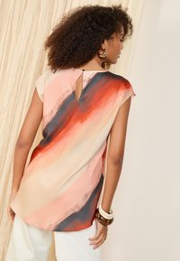 Ärmellose Bluse aus fließendem Stoff, mit einem abstrakten Farbverlauf in Pfirsich, Orange und Dunkelblau sowie einem Rückendetail im Schlüsselaugen-Stil.