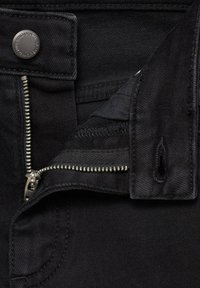 Jeans de mezclilla negra con un cierre de cremallera plateada y botón. La tela presenta una textura suave, costuras visibles y una bragueta abierta.