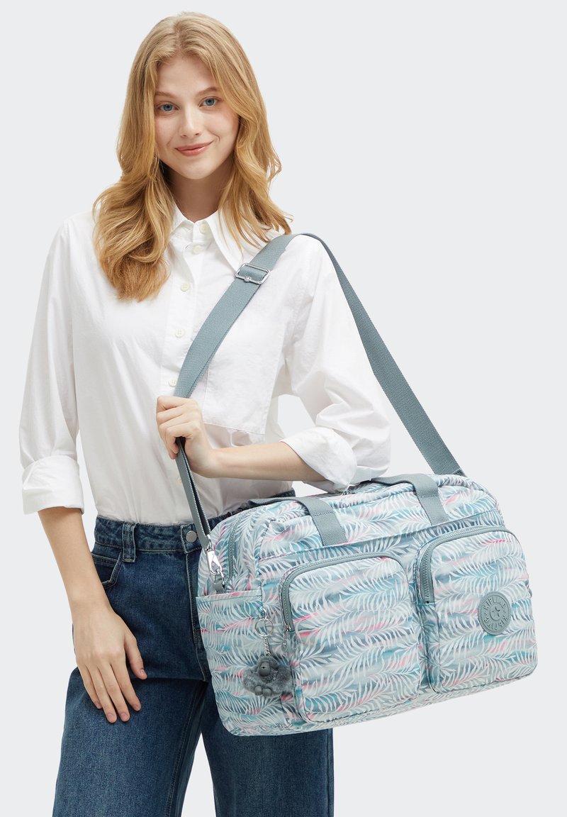 Lichtblauwe sporttas met loofpatronen, meerdere ritszakken en een afneembare schouderriem. Zacht, duurzaam materiaal met een gestructureerde afwerking.