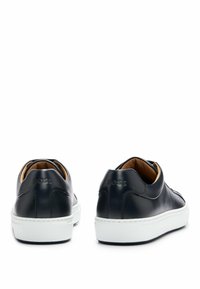 Baskets en cuir bleu marine à finition lisse, semelle en caoutchouc blanche et logo embossé à l'arrière. Design minimaliste avec une forme élancée.