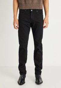Pantalones vaqueros de mezclilla negra con corte recto. Presentan un clásico cierre con botón y cremallera, cinco bolsillos y detalles de costura sutil.
