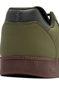 Green shoe with a textured synthetic upper, dark gray heel accent, and a brown rubber sole featuring a geometric pattern.