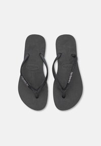 Chinelas de borracha pretas com solas texturizadas e tiras brilhantes. Apresentam a marca Havaianas na tira. Design clássico e minimalista.
