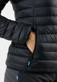 Black puffer jacket with a quilted design, zippered pocket, and Swedish flag accent. Features padded sleeves and smooth texture.