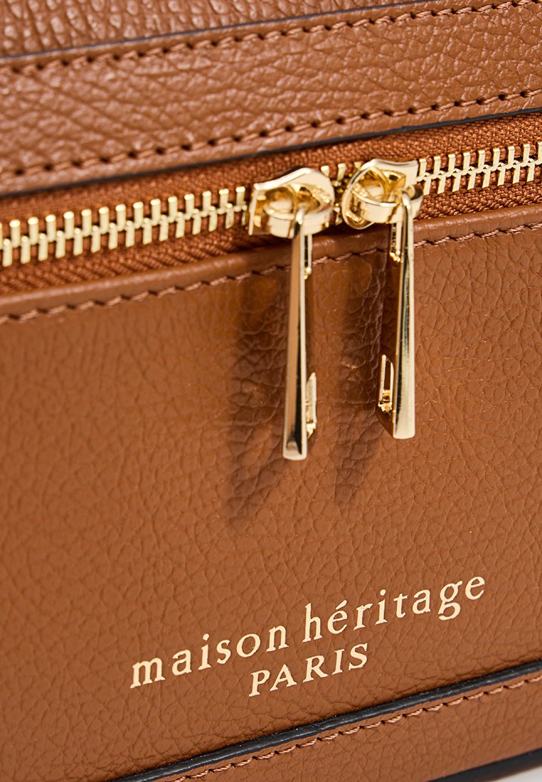 Sac en cuir brun avec une finition texturée, matériel de fermeture éclair doré et logo en relief sur le devant.