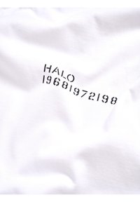Weißer Stoff mit schwarzem gedrucktem Text "HALO", gefolgt von einer Reihe von Zahlen "19681972198", die in einer gebogenen Linie angeordnet sind.