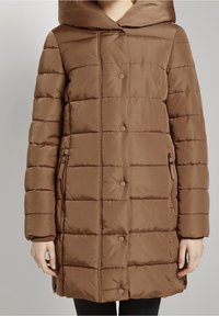 Brun pufferjakke med hætte, quiltet design, trykknapper og sidelommer. Materialet ser glat og isoleret ud.