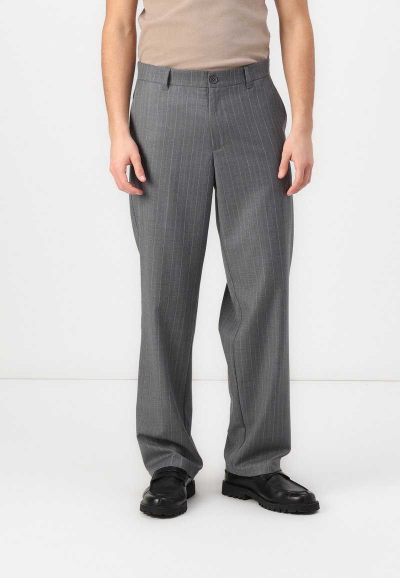 Graue Nadelstreifen-Hose mit geradem Bein, flachem Bund und Knopfverschluss, aus leichtem Stoff gefertigt. Trägt schwarze Schuhe.