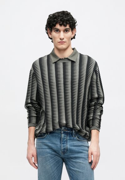 Πλεκτό πουλόβερ σε μαύρο και γκρι με υφασμένο σχέδιο ζιγκ-ζαγκ. Διαθέτει γιακά στη λαιμόκοψη και άνετη εφαρμογή, συνδυασμένο με τζιν μπλε.