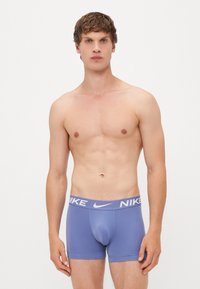 Lilla Nike boxer-shorts med en hvid logo på livet, med en glat tekstur og tætsiddende design.