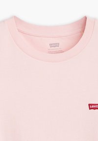 Maglietta in cotone rosa chiaro con scollo rotondo, caratterizzata da un piccolo logo rosso di Levi's ricamato sulla parte sinistra del petto. Tessuto morbido.