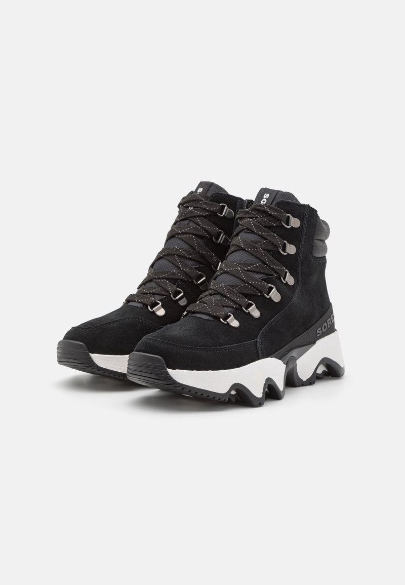 Schwarze Wildleder-Hohe Stiefel mit metallischen Ösen, gemusterten Schnürsenkeln und weißer Zickzack-Sohle. Verfügt über eine Markenkennzeichnung an der Seite zur Identifikation.