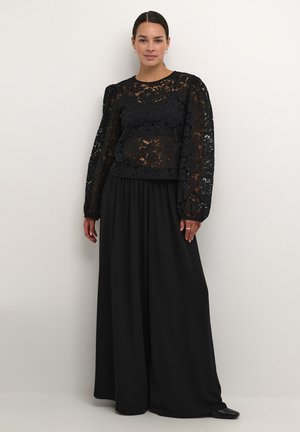 Black lace top with puff sleeves over a flowing black skirt. The top features a floral pattern, while the skirt is smooth and pleated.