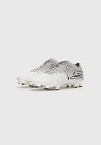Crampons de football blancs et gris avec une tige texturée, un système de laçage, des détails argentés et plusieurs crampons en caoutchouc sur la semelle externe pour une meilleure traction.