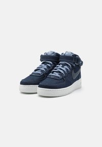 Módní sneakers s vysok ým stříškou v tmavém denimu se světle modrými tkaničkami a akcenty. Mají bílou gumovou podrážku a pásek s detaily loga.