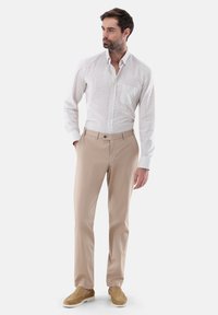 Helles kariertes Hemd mit Knopfverschluss und einer Tasche, kombiniert mit beigen Hosen und beigen Slippern, die eine maßgeschneiderte Passform und glatte Textur zeigen.