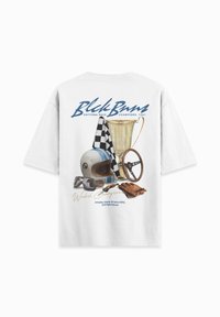 Witte T-shirt met een grafisch ontwerp van race-gerelateerde items: een blauwe gestreepte helm, een zwart-wit geblokte vlag, een trofee en een stuurwiel.