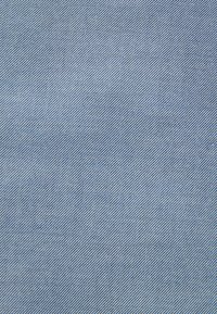 Svijetloplavi denim s finom dijagonalnom rebrastom teksturom, sa tankim bijelim i tamnoplavim prugama raspoređenim po cijeloj površini.