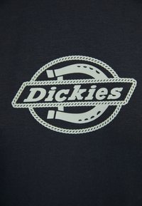 Tmavě šedé tričko s velkým bílým logem ve středu, obsahujícím text "Dickies" a kolem je design lana.