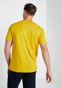 Yellow cotton t-shirt with short sleeves and a rounded neckline, featuring a plain design and a relaxed fit. Back view shown.