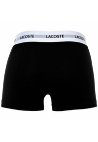 Czarne bokserki męskie wykonane z bawełny, z białym pasem w talii z logo "LACOSTE" i gładką teksturą.