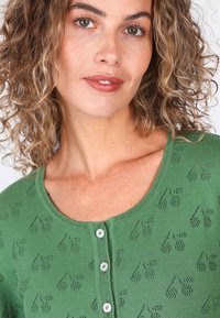Grüner Strick-Top mit Rundhalsausschnitt, Knopfverschluss vorne und einem strukturierten Muster aus kleinen Obstmotiven.