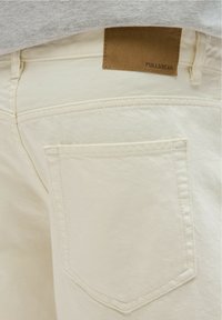 Bež tkaninske hlače s stražnjim džepom, teksturiranom površinom i smešnim kožnim detaljem s utisnutim natpisom "PULL&BEAR".