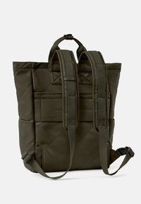 Sac à dos matelassé vert olive en nylon, doté de bretelles ajustables, de poches frontales et d'une poignée supérieure. Texture lisse avec des détails matelassés.