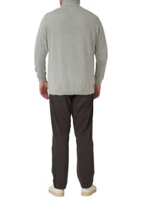 Szary sweter z dzianiny o wysokim kołnierzu, zestawiony z ciemnobrązowymi spodniami i białymi trampkami. Swobodny wygląd, fakturowana dzianina i dopasowany krój.