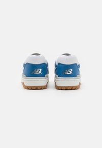 Chaussure de sport bleue et blanche avec une tige en mesh texturé, une semelle extérieure en caoutchouc et un détail de logo sur le talon. Elle présente une forme arrondie et des lacets.