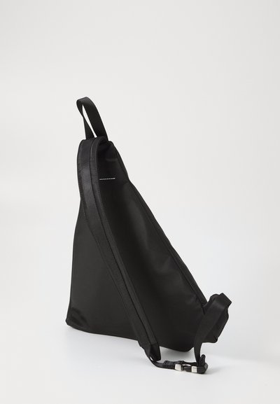 Svart, triangulär axelväska med en slät nylonutsida, justerbar rem och minimalistisk design som har en subtil sömdetalj.