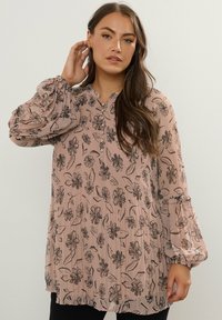 Langærmet bluse i blødt pink stof med et blomsterprint i sort. Har et plisseret design og elastiske manchetter. V-udskæring med knapdetalje.