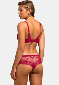 Ensemble de lingerie en dentelle bordeaux comprenant un soutien-gorge et une culotte avec de délicats motifs floraux. Le soutien-gorge dispose de bretelles ajustables, et la culotte présente un détail en forme de clé à l'arrière.