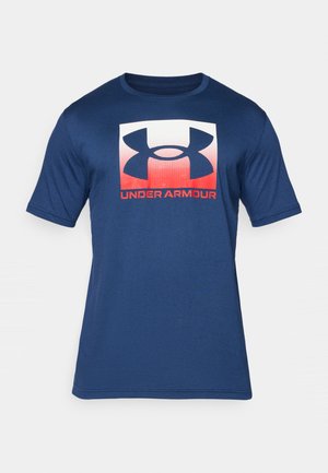 Tamsiai mėlynas trumpomis rankovėmis marškinėliai, pagaminti iš minkštos medžiagos, su dideliu baltu ir raudonu "Under Armour" logotipu priekyje.