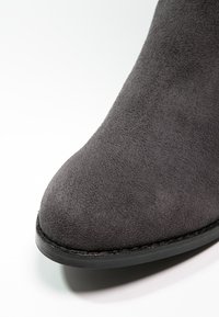 Gray suede ankle boot with a pointed toe and a black rubber sole. The upper features a smooth texture with no visible hardware or accents.