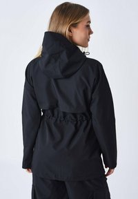 Giacca nera impermeabile con cappuccio regolabile, vestibilità rilassata, vita elastica e tessuto texturizzato. Presenta maniche lunghe e una lunghezza media.