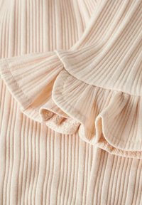 Prążkowana tkanina w delikatnym różowym kolorze z falistą falbaną na krawędzi. Tekstura jest gładka z pionowymi liniami i subtelnym połyskiem.