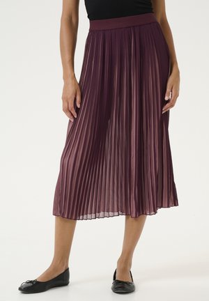 Plissé midi skirt in deep burgundy with a soft, flowing texture and an elastic waistband. Styled with black flat shoes.